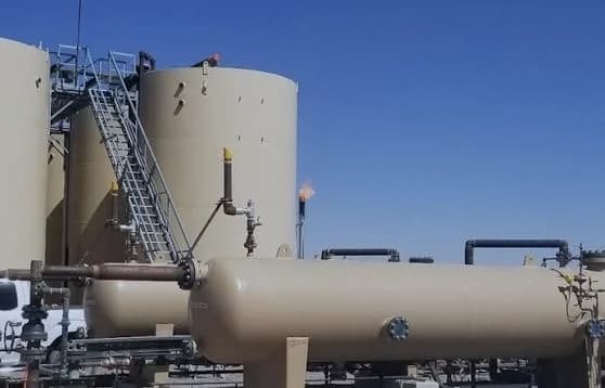 Oil battery with storage tanks, a horizontal separator vessel and flare stacks.